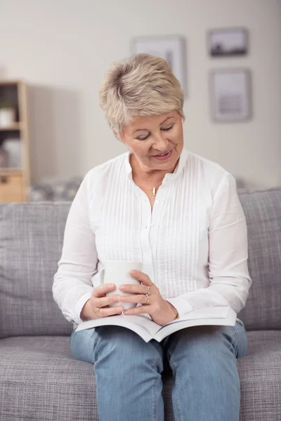 Привлекательная женщина средних лет, сидящая и читающая — стоковое фото
