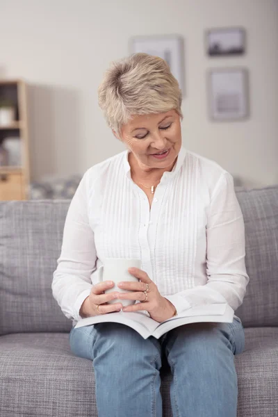 Attractive middle-aged woman sitting reading — 图库照片