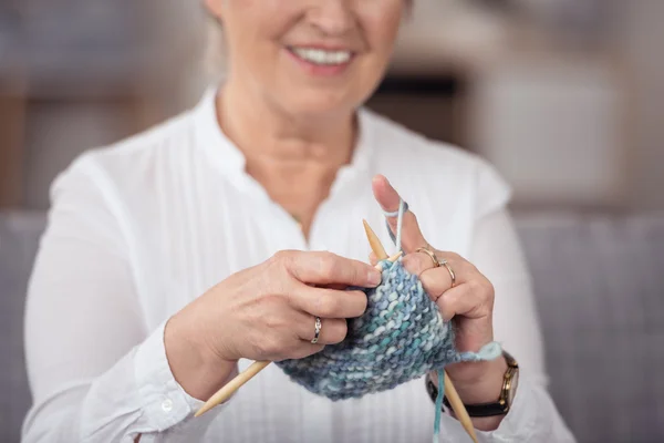 Middle-aged woman knitting a garment — Stok fotoğraf