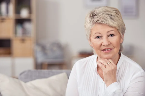 Frau mittleren Alters auf dem Sofa und blickt in die Kamera — Stockfoto