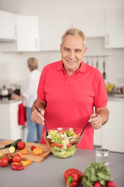 Glücklicher Senior mit Gemüsesalat in der Küche — Stockfoto