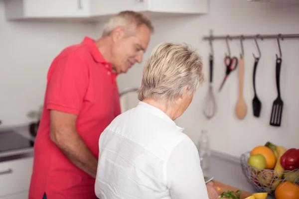 Старшая пара готовит свежую еду на кухне — стоковое фото