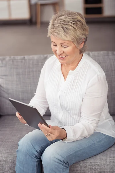 Glückliche Seniorin mit Tablet auf der Couch — Stockfoto