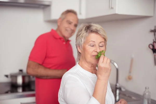 Esposa mayor oliendo hierbas frescas en la cocina — Foto de Stock