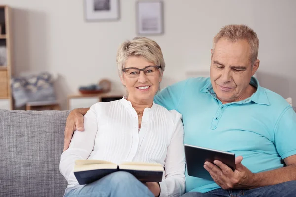 Casal em destaque no sofá com livro e tablet — Fotografia de Stock