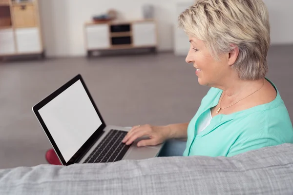 Glückliche Seniorin mit Laptop auf der Couch — Stockfoto