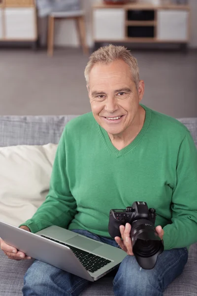 Fotografo senior sorridente con computer portatile e DSLR — Foto Stock