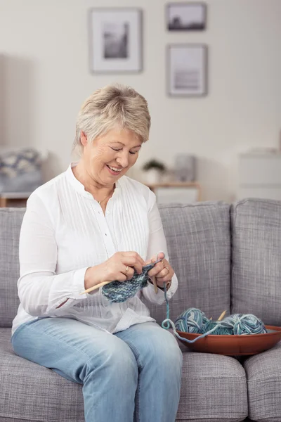 Glückliche Frau mittleren Alters, die mit Garn strickt — Stockfoto