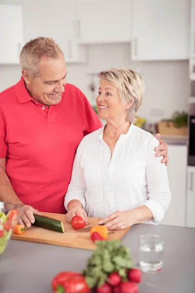 Старшая пара улыбается друг другу на кухне — стоковое фото