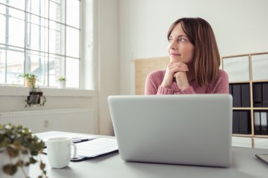 Young woman sitting at her desk daydreaming clipart