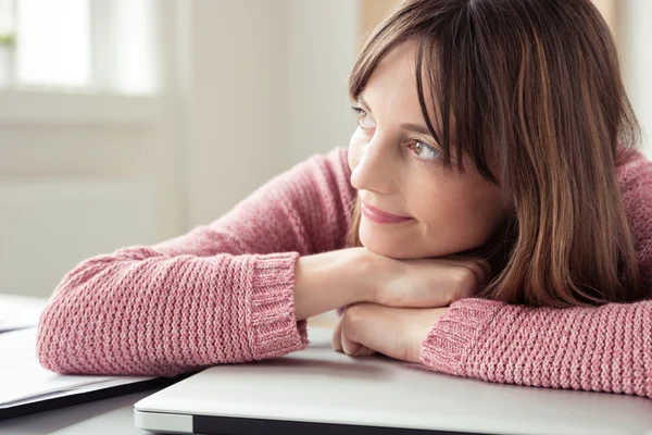 Smiling young woman daydreaming at the office — Stockfoto