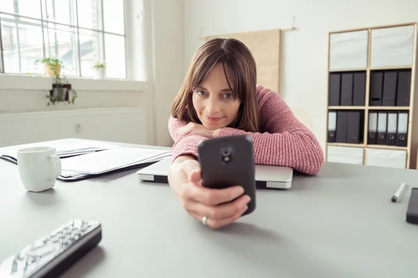 Bored woman in the office checking her mobile — Zdjęcie stockowe