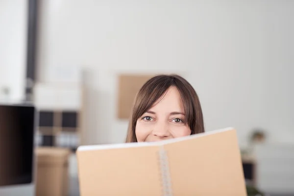 Woman Looking at the Camera Over the Top of Notes — Stockfoto