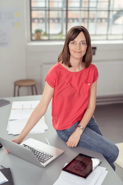 Donna seduta sul tavolo con computer portatile e documenti — Foto Stock