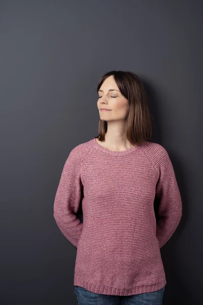 Mujer pensativa apoyada contra la pared gris — Foto de Stock