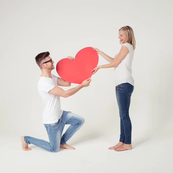 Dulce joven pareja sosteniendo gran corazón rojo —  Fotos de Stock