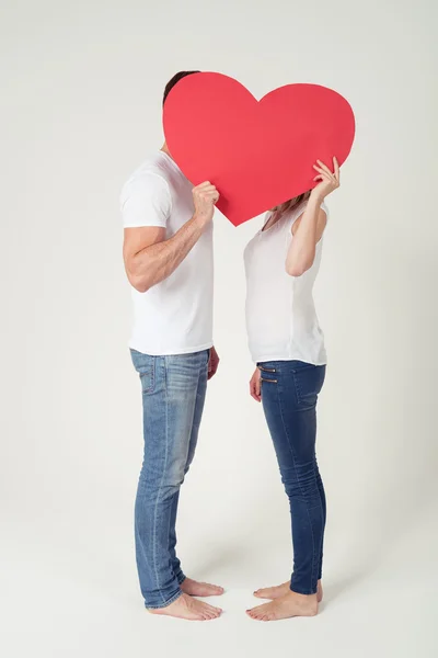 Paar bedeckt ihre Köpfe mit leerem roten Herz — Stockfoto