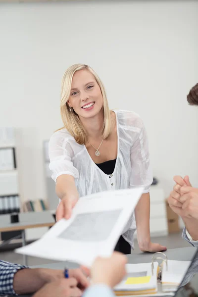 Lachende kantoor vrouw die een document overhandigt — Stockfoto