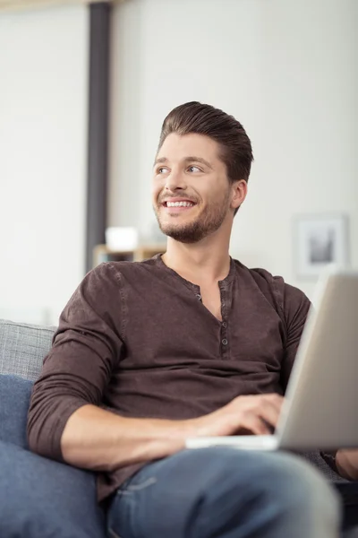 Fechar o homem bonito com laptop no sofá — Fotografia de Stock