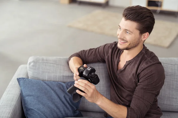 Homem com câmera DSLR no sofá em vista de ângulo alto — Fotografia de Stock