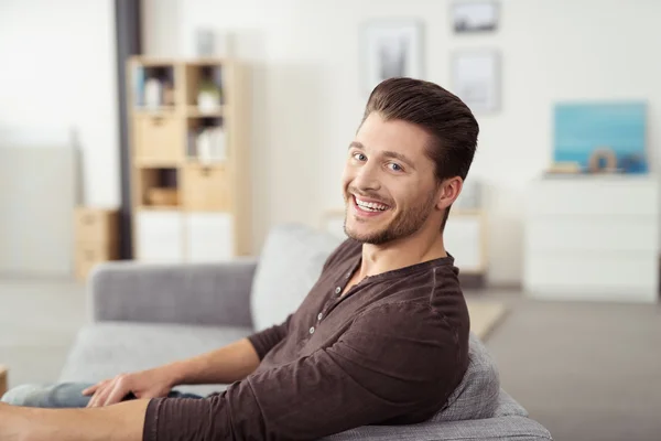 Alegre guapo chico en sofá mirando cámara —  Fotos de Stock