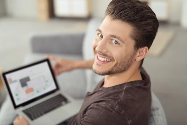 Joyeux jeune homme beau avec ordinateur portable au canapé — Photo