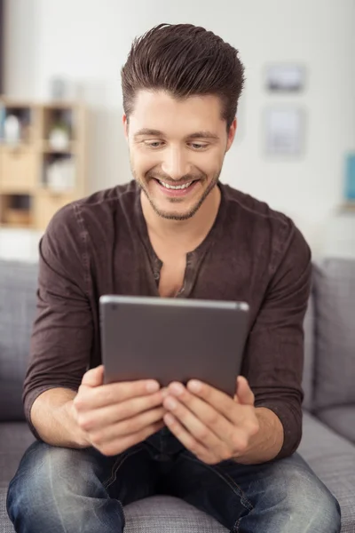 Happy Attractive Guy on Couch Holding his Tablet — Stock Fotó