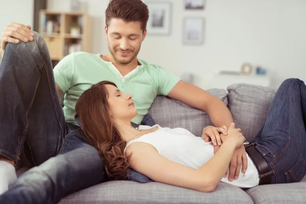 Romantisches junges Paar entspannt auf der grauen Couch — Stockfoto