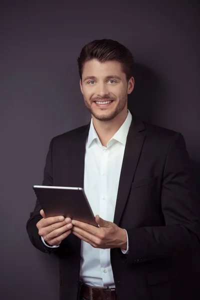 Hombre de negocios guapo con tableta contra la pared gris —  Fotos de Stock