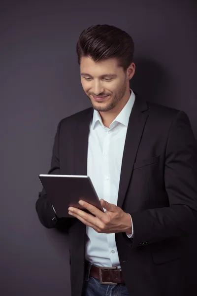 Empresario sonriente usando tableta contra pared gris — Foto de Stock