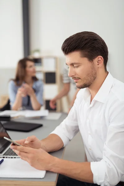 Geschäftsmann mit Telefon am Tisch beschäftigt — Stockfoto