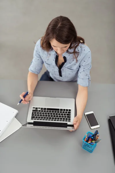 Junge Büroangestellte liest auf Laptop am Schreibtisch — Stockfoto