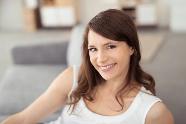 Belle femme sur un canapé souriant à la caméra — Photo