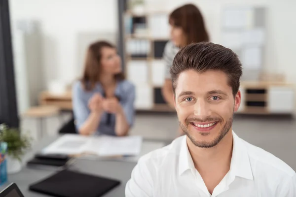 Молодой бизнесмен в офисе улыбается в камеру — стоковое фото