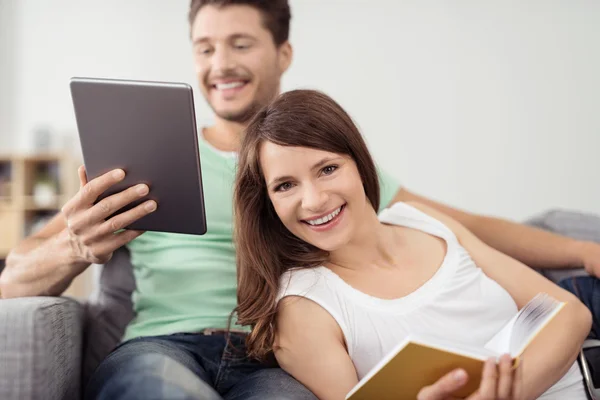 Coppia con Libro e Tablet Relax sul Divano — Foto Stock