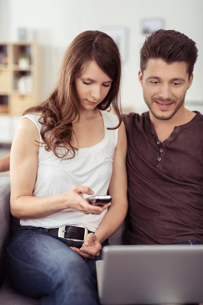 Casal doce no sofá com laptop e telefone — Fotografia de Stock