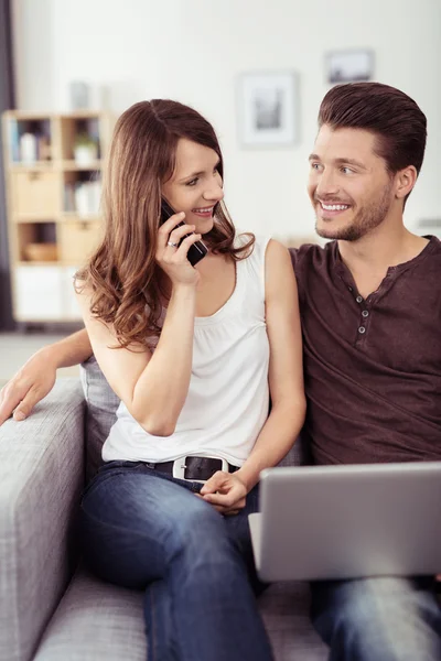 Casal com laptop conversando com alguém no telefone — Fotografia de Stock