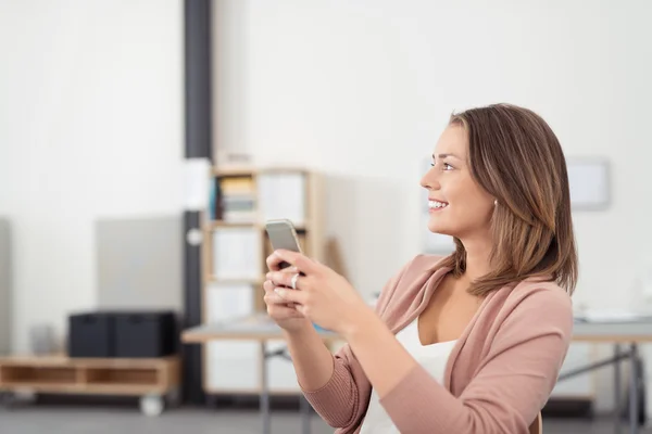 Šťastná promyšlené žena drží její mobilní telefon — Stock fotografie