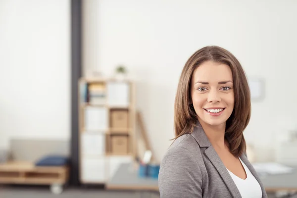 Graziosa dipendente in ufficio sorridente a camera — Foto Stock