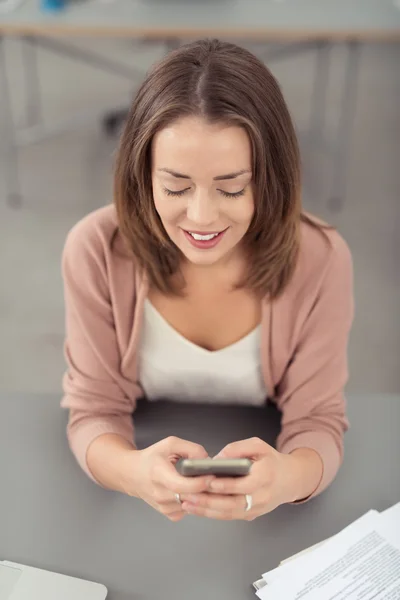 Happy Woman à la table textos sur son téléphone — Photo