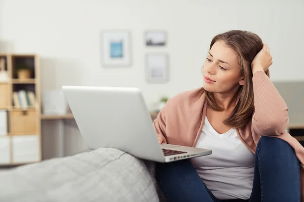 Женщина с ноутбуком сидит на диване в гостиной — стоковое фото