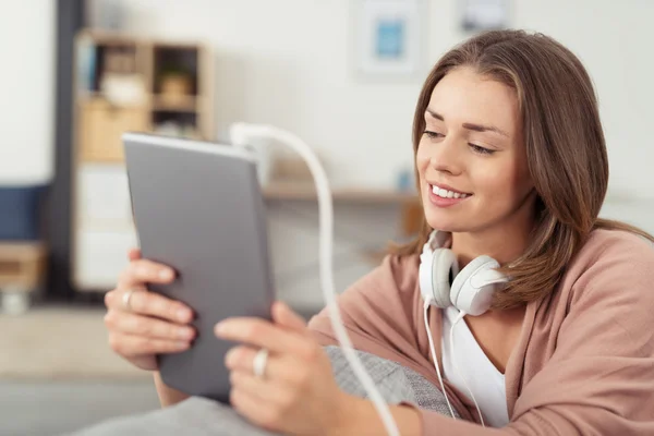 Glückliche junge Frau schaut etwas auf ihrem Tablet — Stockfoto