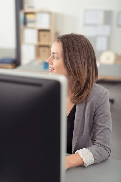 Lachende vrouw op haar Bureau op zoek in afstand — Stockfoto