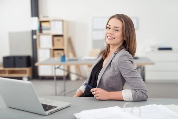 Mulher bonita escritório em sua mesa sorrindo para a câmera — Fotografia de Stock