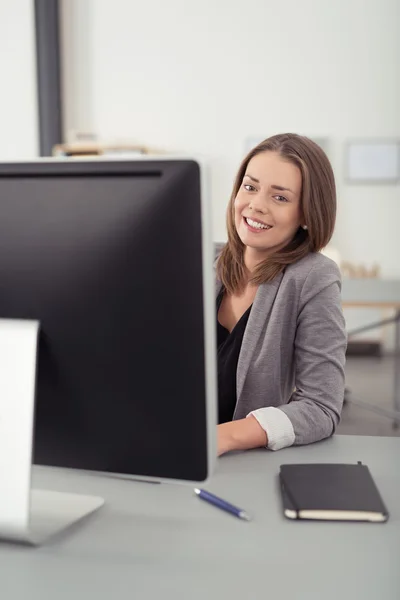 Mulher bonita em sua mesa sorrindo para a câmera — Fotografia de Stock