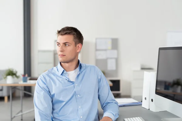 Fundersam unga Office Man sitter vid sitt arbetsbord — Stockfoto