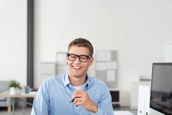 Glücklicher junger Büromensch sitzt an seinem Arbeitsplatz — Stockfoto