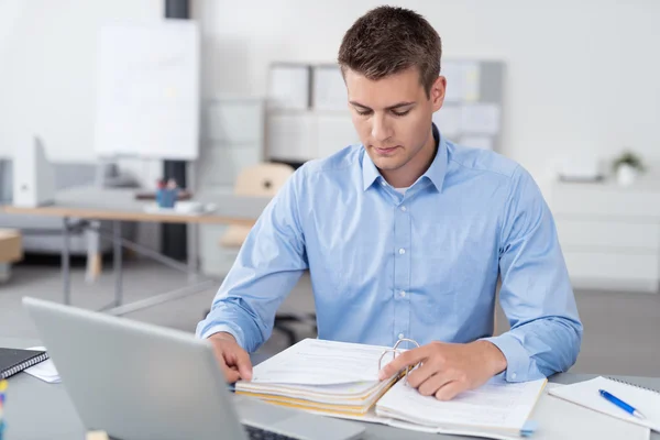 Jungunternehmer liest an seinem Schreibtisch Dokumente — Stockfoto