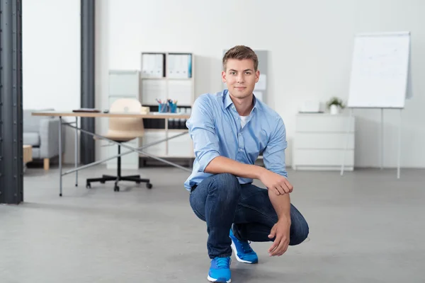 Smiling Office Man Squatting Inside his Workplace — Stock Photo, Image