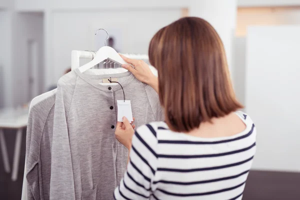 Woman Looking at Shirt Price Tag in Clothing Store — Zdjęcie stockowe